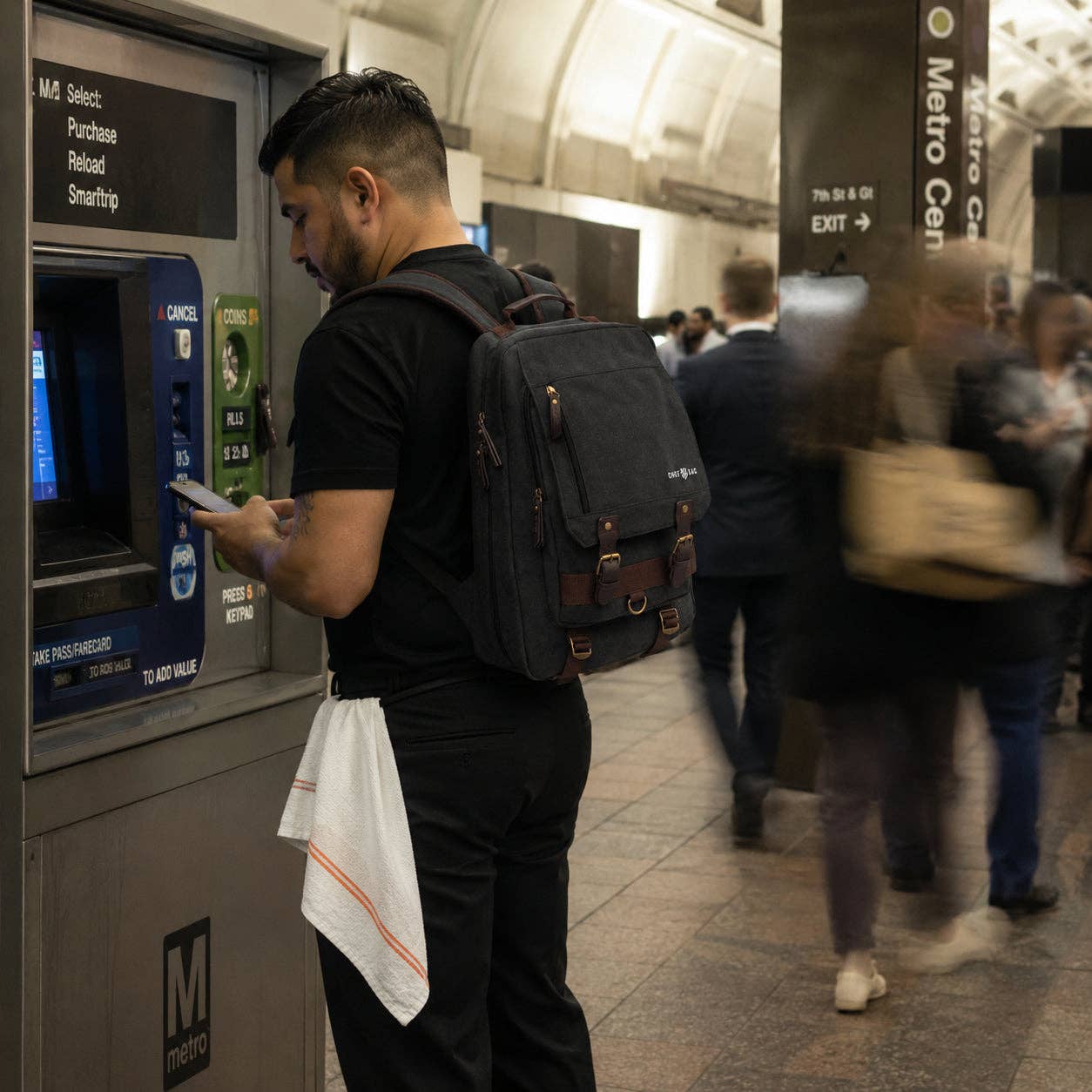 Chef with a backpack using an ATM machine in a busy subway station.