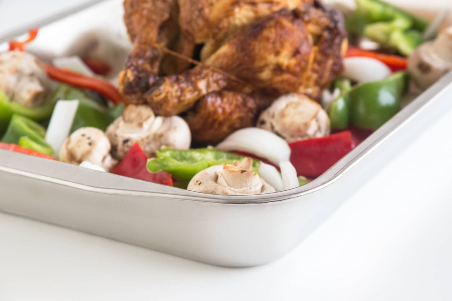 Roasted chicken with vegetables in a roasting pan.