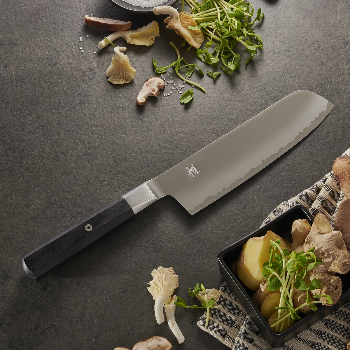 Miyabi Koh Nakiri on black textured background with mushrooms and greens.