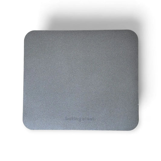A rectangular gray carbon baking steel with rounded corners and the debossed brand name 'baking steels' near the bottom, shown on a white background with a soft drop shadow.