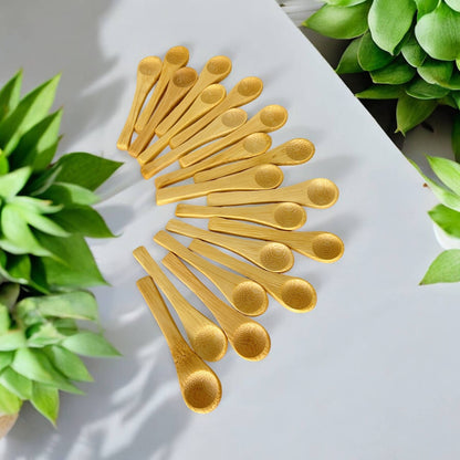 bamboo spoons on a white surface with green plants in the background