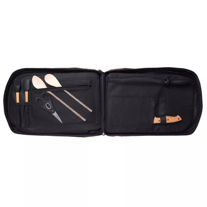 An open black carrying case displaying a set of barbecue tools, including wooden spatulas, metal scissors, and a knife with a tan handle, arranged neatly on a solid white background.