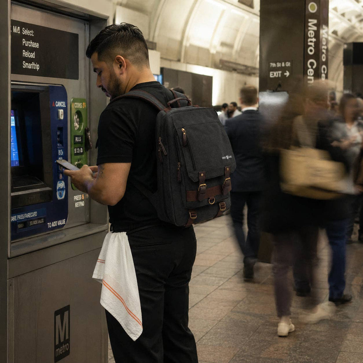 Chef with a backpack using an ATM machine in a busy subway station.