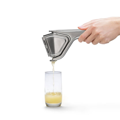 Stainless steel fluicer juicing a lemon into a glass on a white background