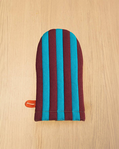 Striped oven mitt with blue and red stripes on a wooden surface