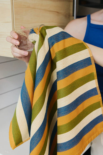 Person holding a colorful striped towel with a drink in a casual setting
