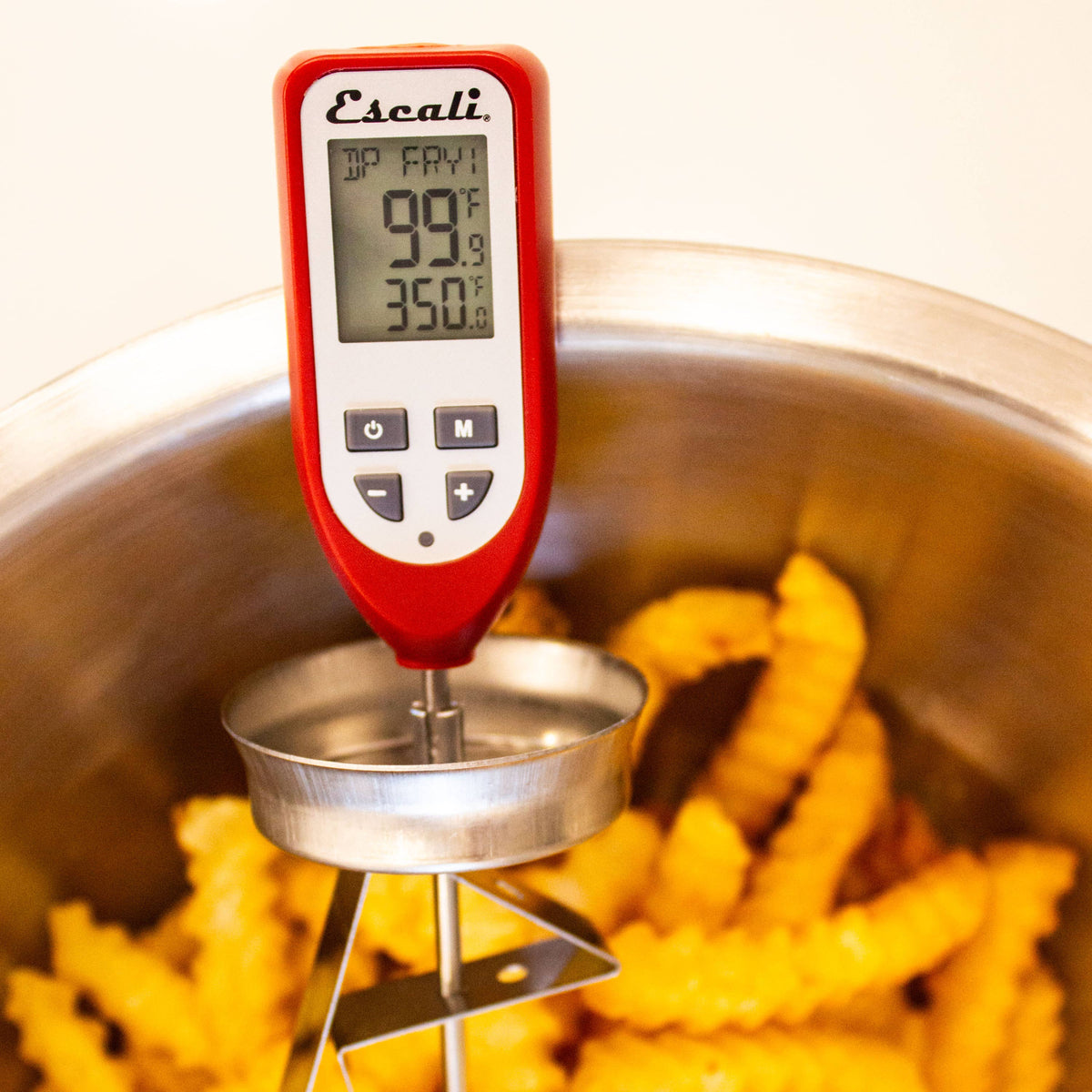 Digital thermometer measuring oil temperature in a pot with frying food
