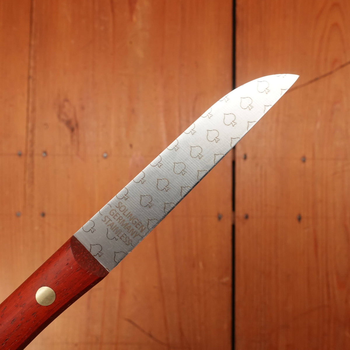Knife with a red handle and engraved blade on a wooden background