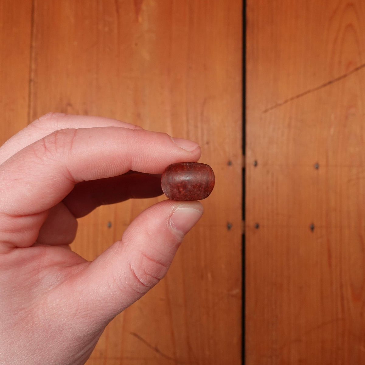 Hand holding a small knife against a wooden background