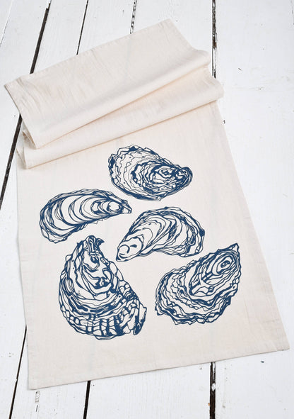 White tea towel with blue oyster prints on white wood.