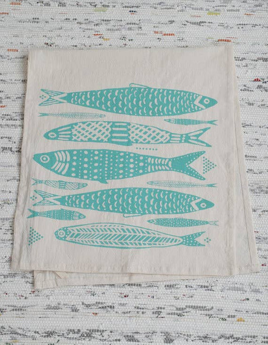A mint green tea towel with a pattern of fish printed across the bottom half.