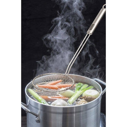 Steaming pot with vegetables and a strainer on a black background