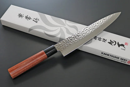 Japanese chef's knife with a wooden handle on a dark surface, featuring the brand 'Kanetsune Seki'.