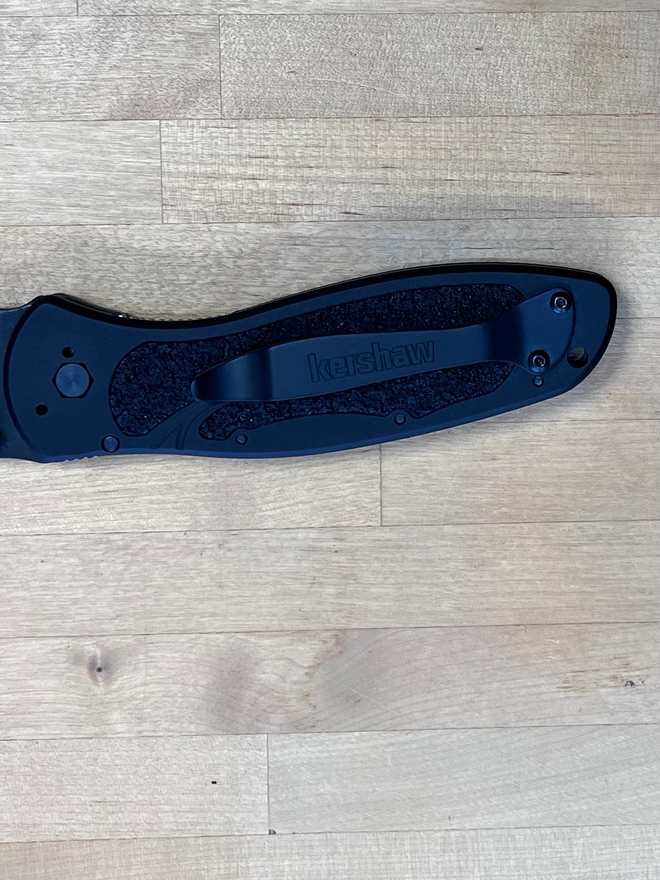 Close up of clip on black folding knife on wood cutting board.