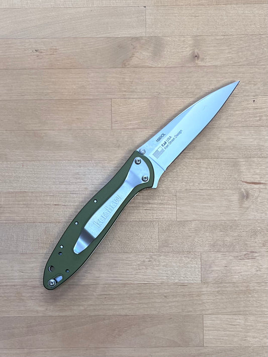Folding knife with green handle on a wooden surface