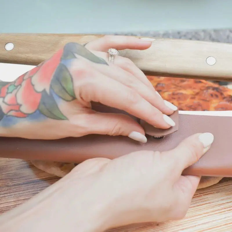 Tattooed hands snapping a leather sheath onto Rocker Cutter, with pizza in the background