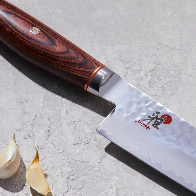 Close up of Miyabi logo on knife on textured white background.