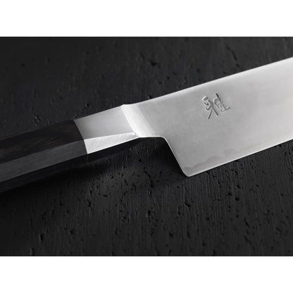 Close up of bolster, Handle-, and heel of a chef knife on a textured black background.