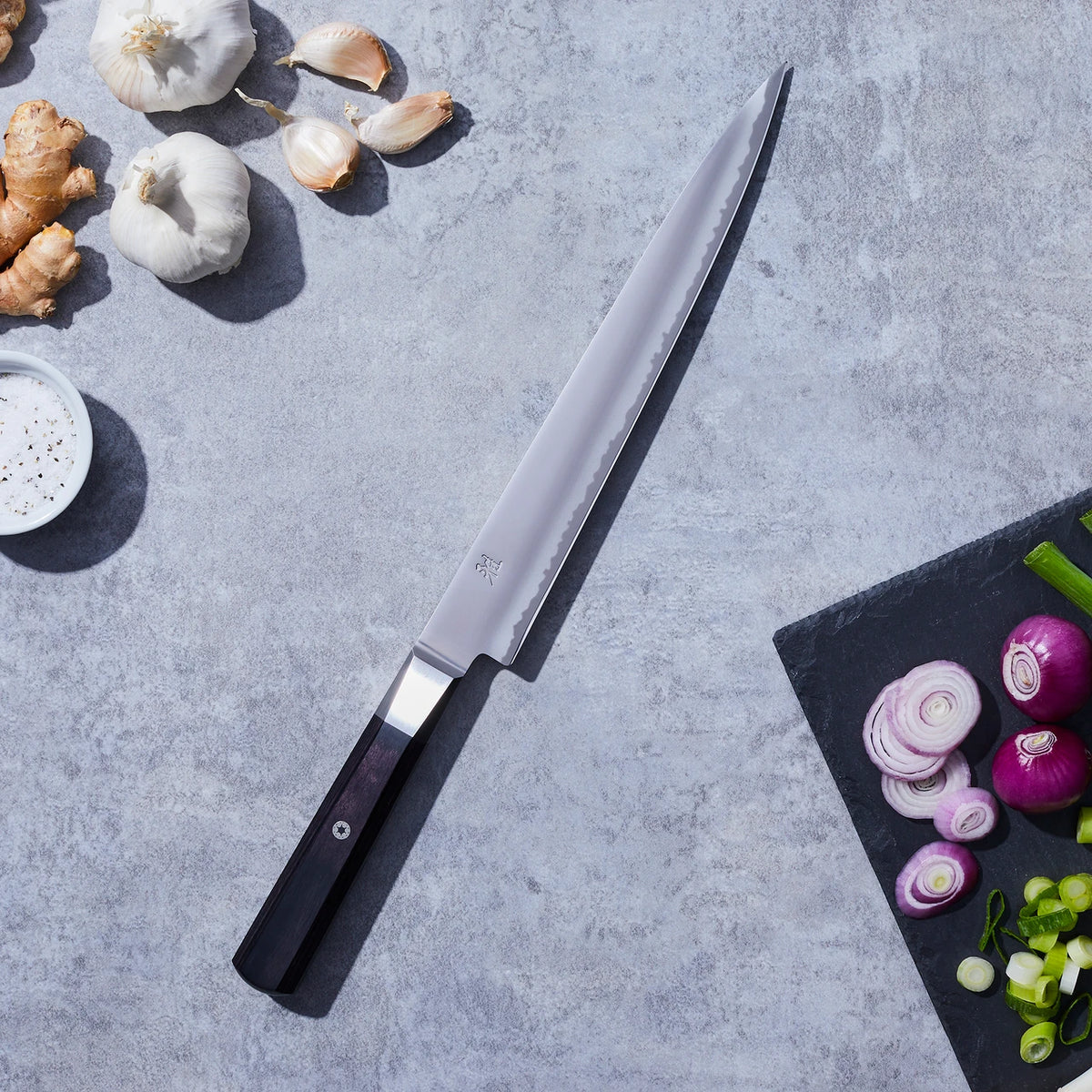 Miyabi Koh Sujihiki on a concrete background with various vegetables.