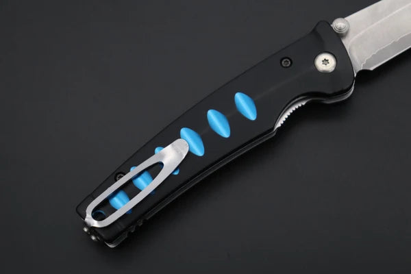 A close-up of a folding pocket knife with a black handle, bright blue accent inserts, and a silver clip, shown on a dark gray background.