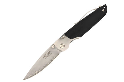 A folding pocket knife with a black handle and a silver steel blade, shown open against a plain white background. The blade is engraved with the brand name 'MCUSTA'.