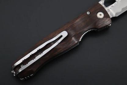 A close-up of a folding pocket knife with a dark brown wood-grain handle and a silver metal clip, shown on a dark gray background.