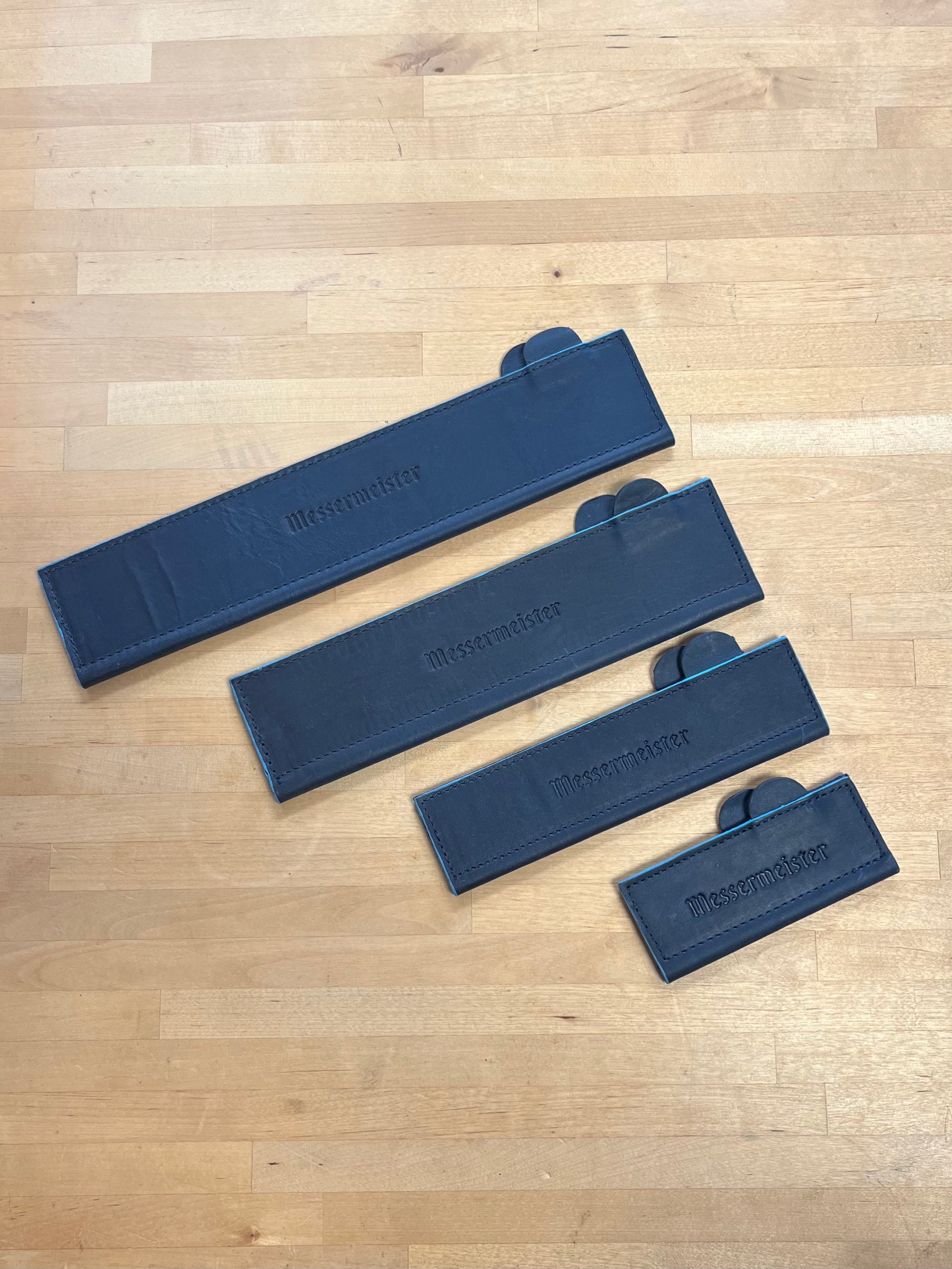 Set of blue leather knife guards on a wooden cutting board