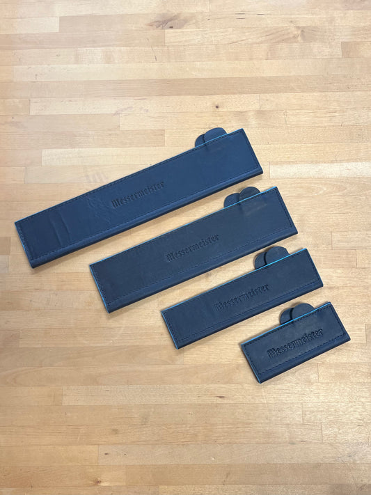 Set of blue leather knife guards on a wooden cutting board
