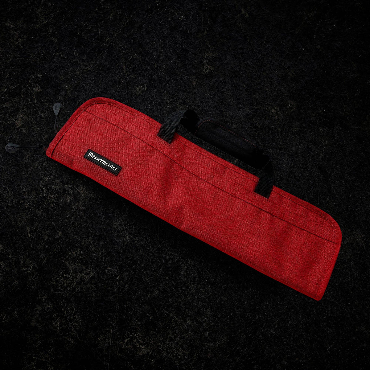 Red knife bag with a black handle on a dark textured background