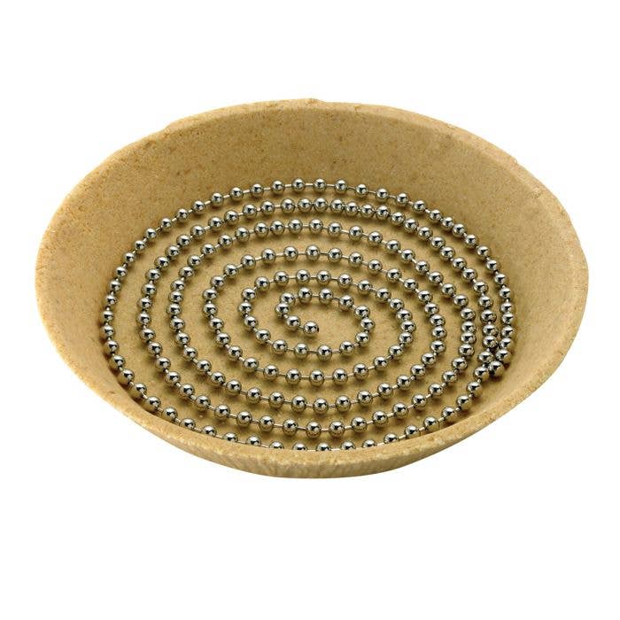 Round beige mat with a spiral pattern of small metal pie weights on a white background