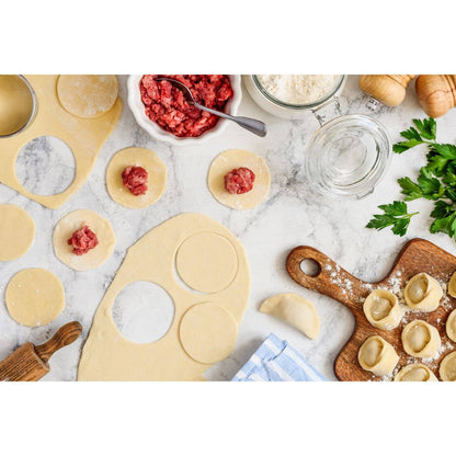 In process of making homemade dumplings with ingredients on a marble surface.