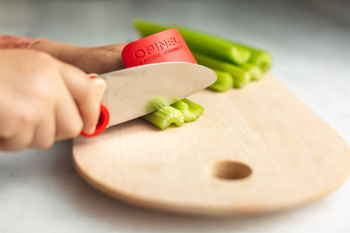 Child cutting celery on wood cutting board
