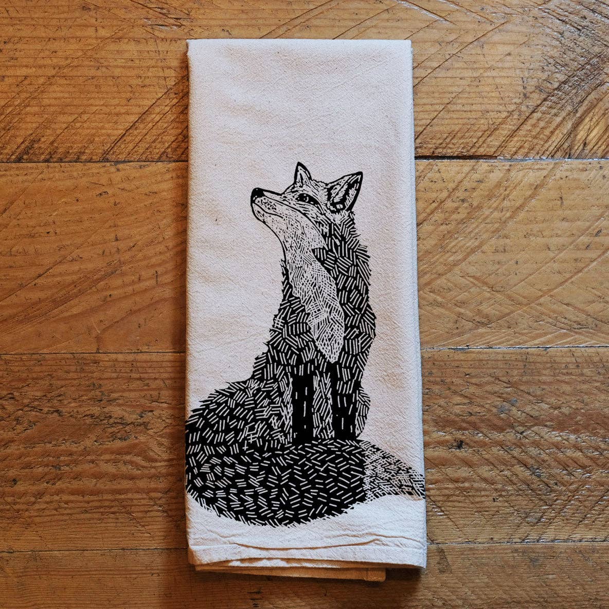 White towel with black fox print on wooden background.