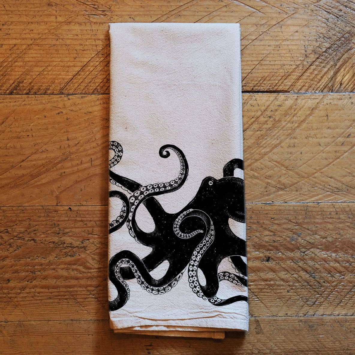 Folded towel with black octopus design on a wooden surface